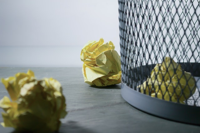 trash bin with crumpled up pieces of yellow paper